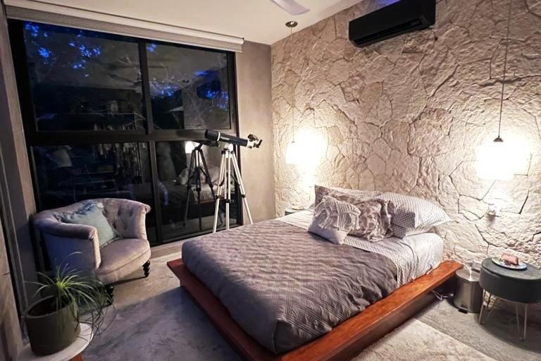 a bedroom with a bed and a chair and a camera at Tulum jungle penthouse in Chemuyil