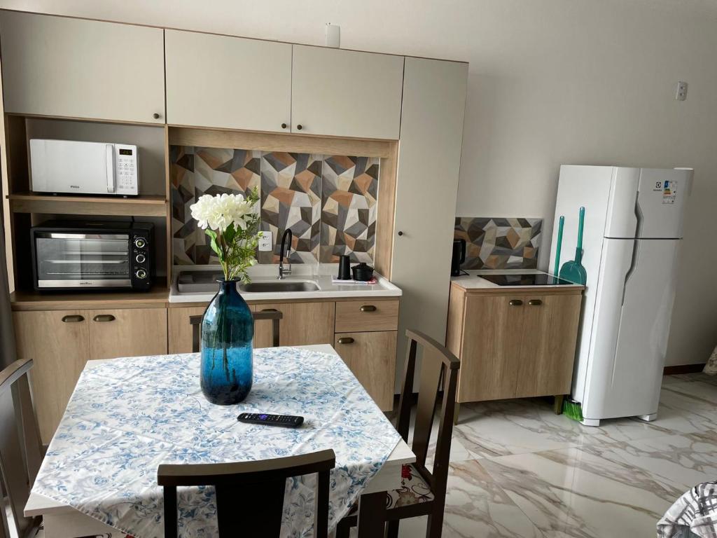 a kitchen with a table with a vase of flowers on it at Residencial Europa in Bombinhas