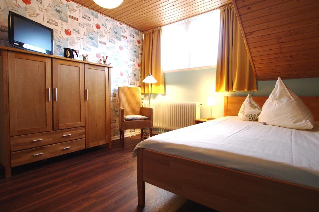 GastHaus Hotel Bremen في بريمين: غرفة نوم مع سرير وتلفزيون على الحائط