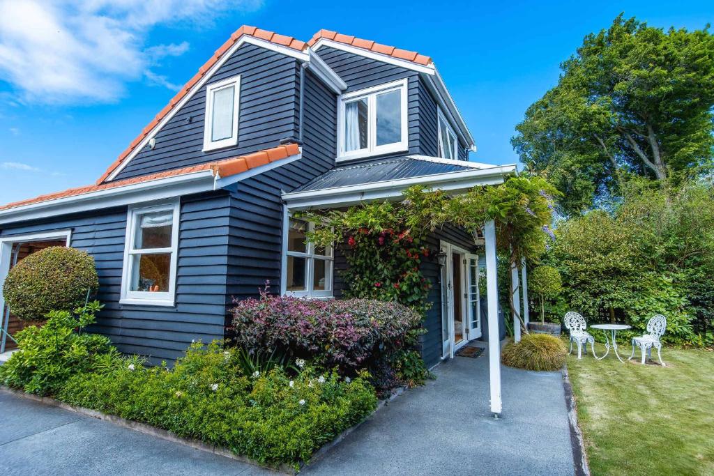 a black house with two chairs in front of it at Black Cottage - Beautiful Central Cottage for Two in Rotorua