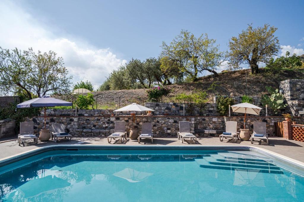 una piscina con sedie e ombrelloni di The Lemon Tree a Taormina