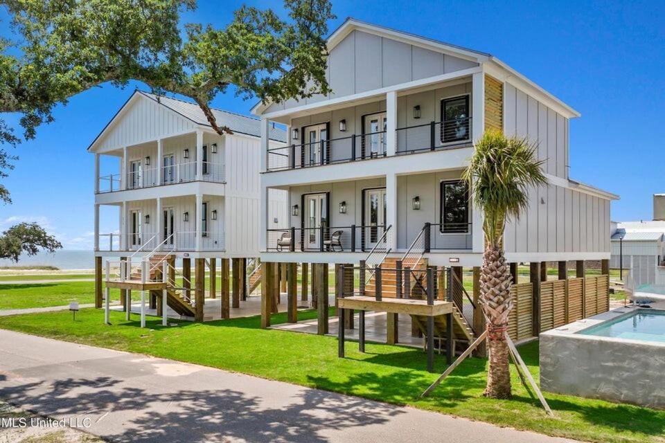 a large white house with a palm tree and a pool at Beach Retreat in Gulfport