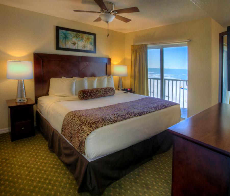a hotel room with a bed and a balcony at Sunset Vistas Two Bedroom Beachfront Suites in St Pete Beach