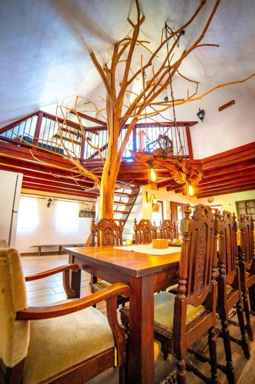 a dining room with a tree on the ceiling at Peter Cottage in Petrilaca de Mureş