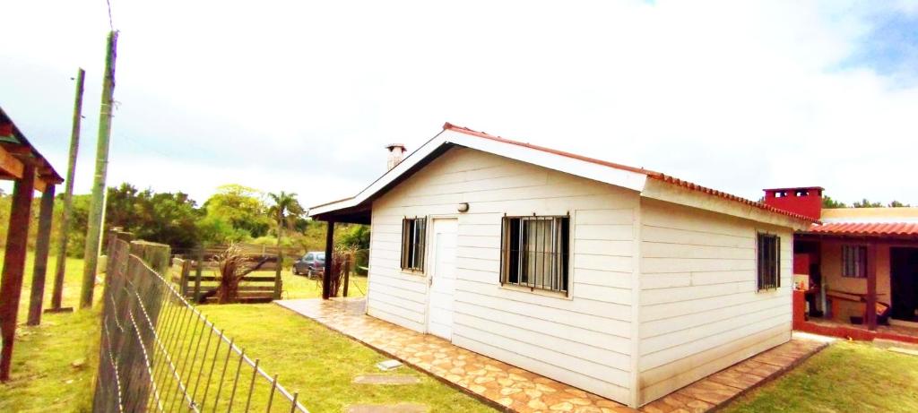 een klein wit huis met een hek eromheen bij Lo de Chachi in Punta Del Diablo