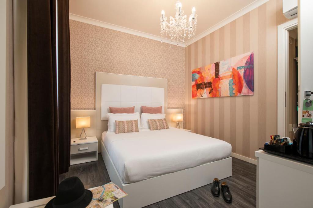 a bedroom with a white bed and a chandelier at San Pietro Suites in Rome