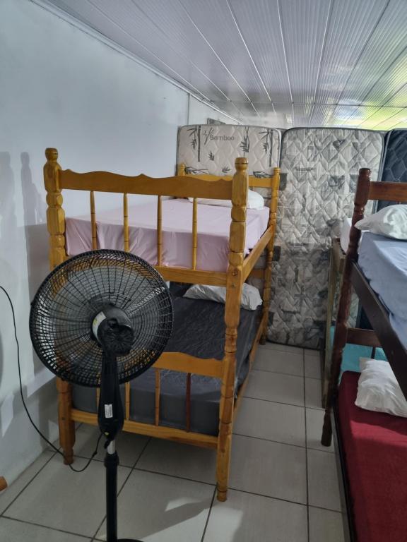 a fan in a room with two bunk beds at Oca do Ric in Imbituba
