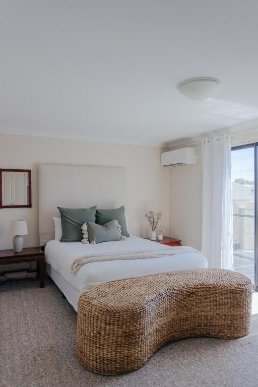 a white bedroom with a large bed and a window at Pet Friendly Townhouse in Geraldton
