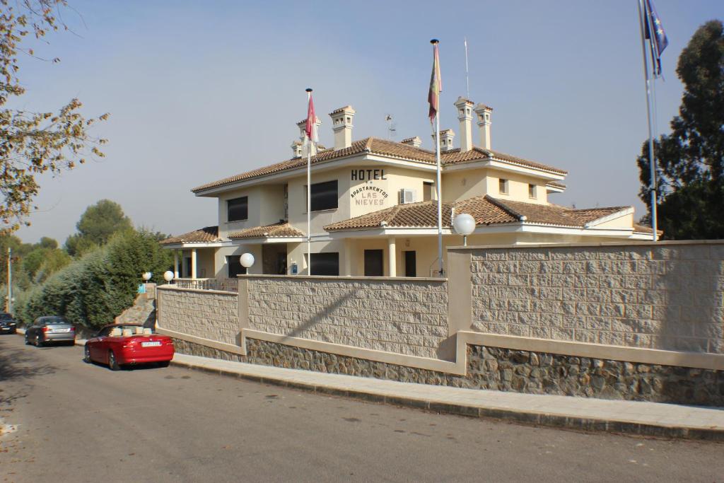 a house on a wall with a red car parked in front at Hotel Las Nieves in Las Nieves