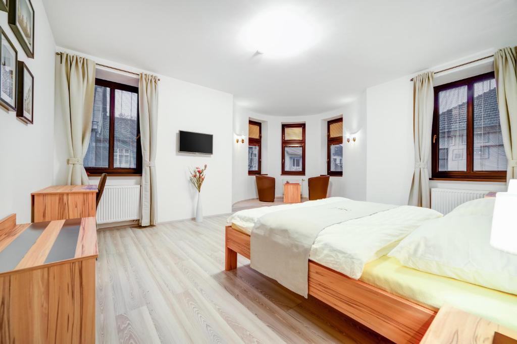 a white bedroom with two beds and a television at Penzion Královská Cesta in Brno