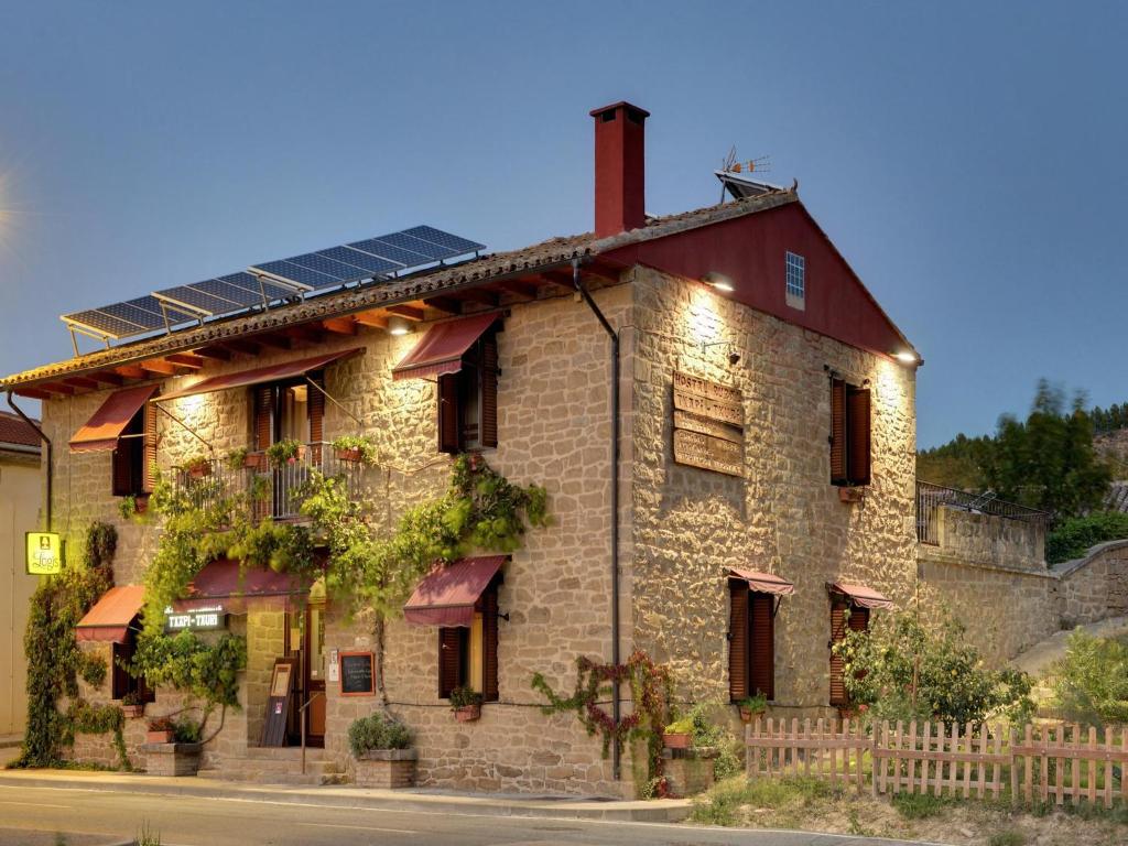 Murillo el Fruto的住宿－Hostal Rural Txapi Txuri Logis Hotels，一座古老的石头房子,上面设有太阳能电池板