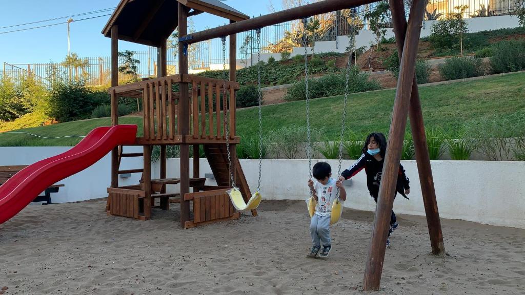 Eine Frau und ein Kind spielen auf einem Spielplatz in der Unterkunft Nuevo y Bello Departamento Cerro Placeres Valparaíso Vista al Mar in Viña del Mar