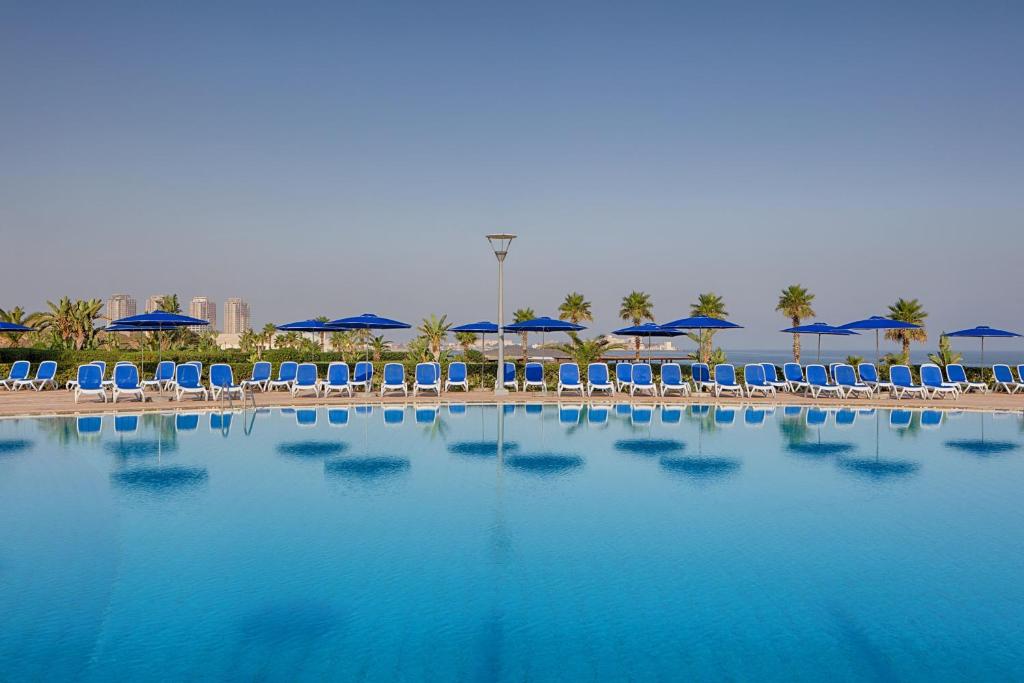克拉布德品斯Sheraton Club des Pins Resort的配有椅子和遮阳伞的大型游泳池