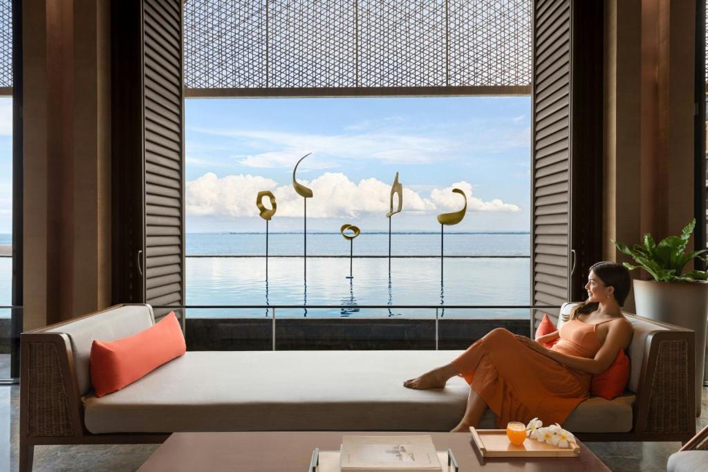 a woman sitting on a couch in front of a window at Sheraton Cebu Mactan Resort in Mactan