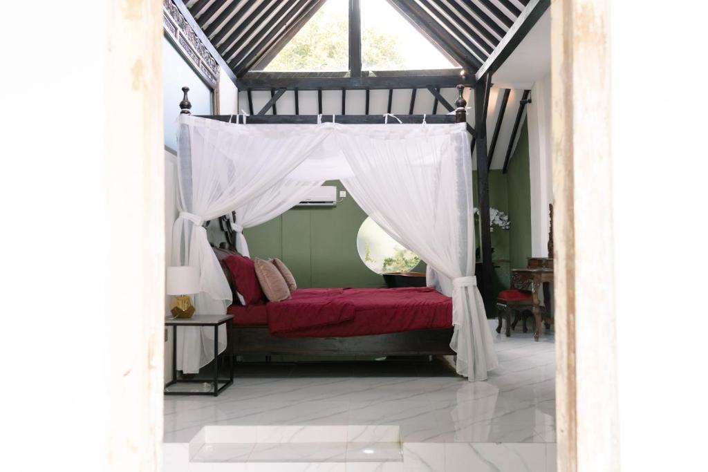 a bedroom with a red bed with a canopy at Villa Tria Laweyan Solo in Purwosari