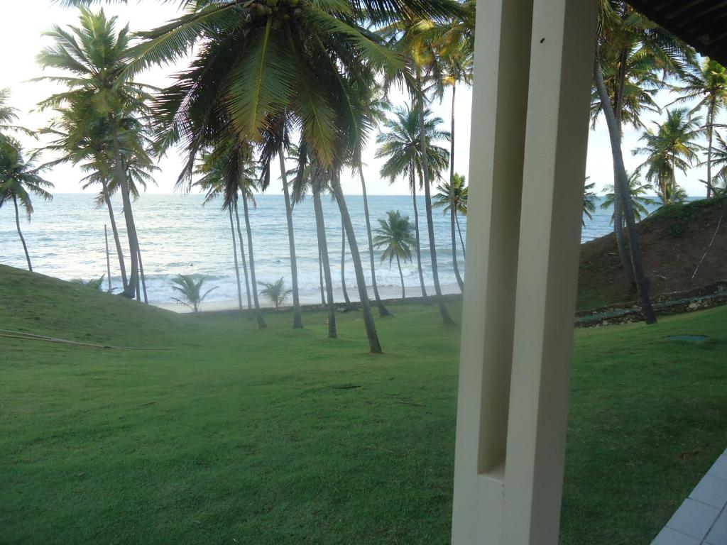 a view of the ocean and palm trees from a house at Ekoara Bangalos in Jacumã