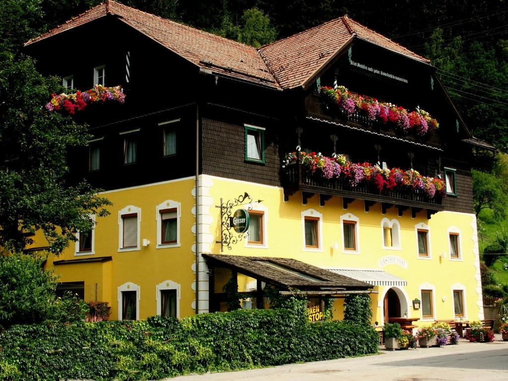 ein gelbes Gebäude mit Blumenkästen drauf in der Unterkunft Gasthof Post in Eisentratten