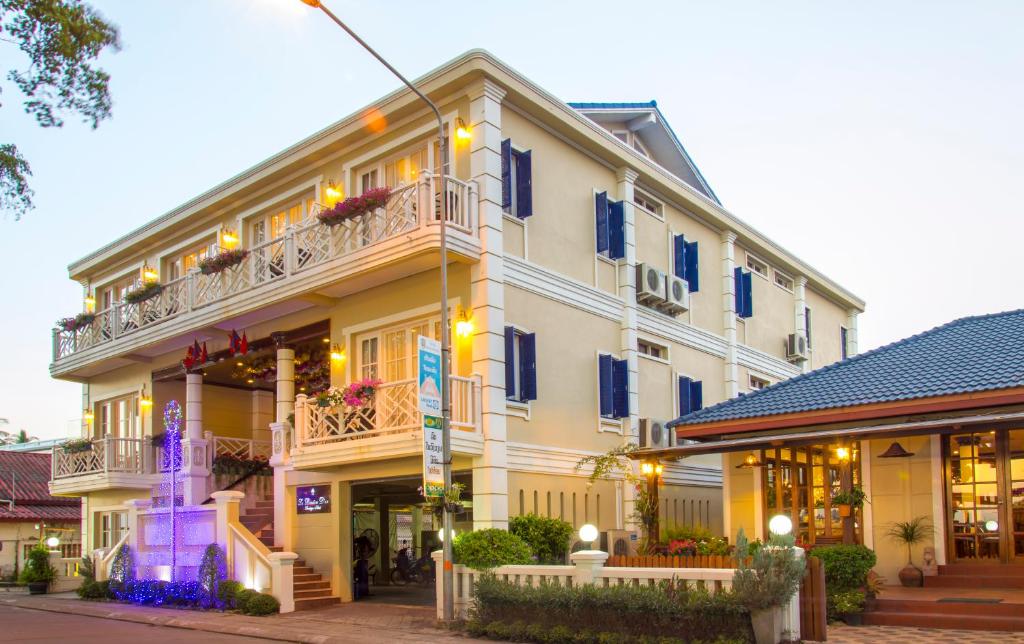 a large white building with balconies on a street at Le Bouton D'or Boutique Hotel in Thakhek
