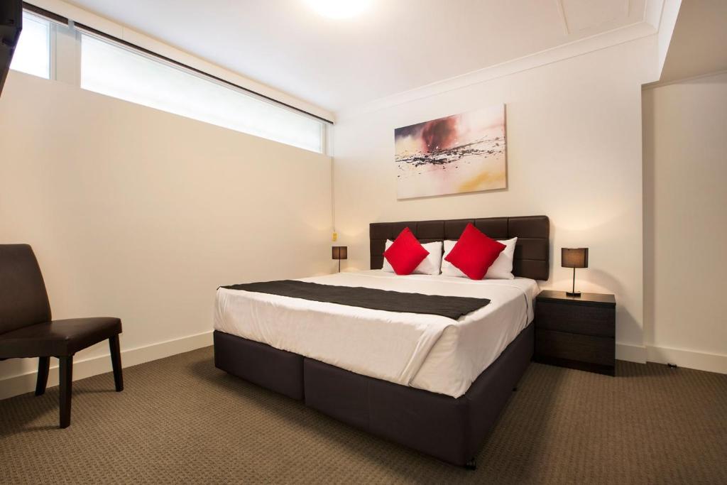 
a hotel room with a bed, chair, and nightstand at Enfield Hotel in Adelaide
