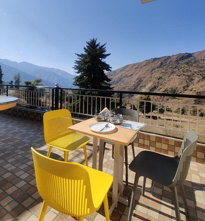 MiānīTSR Inn By Xplore Mantra Hotel and Cafe, Nagtibba的露台上的桌子和椅子，背景是群山