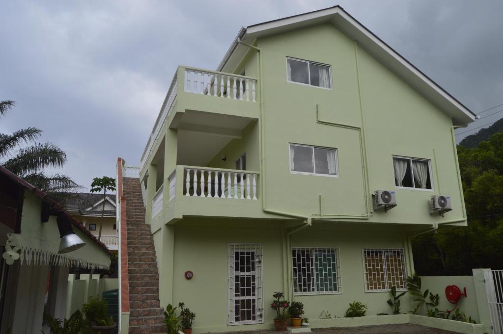 a green and white house with a balcony at Chez Payet Airport Guesthouse in Pointe Larue