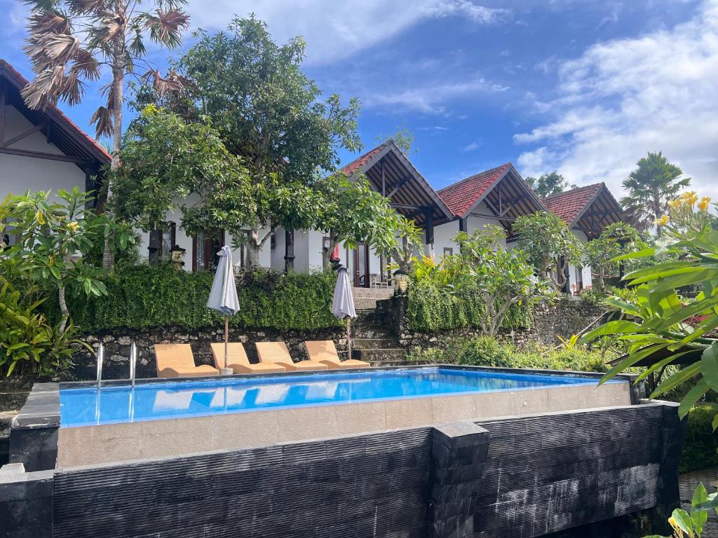 a swimming pool in front of a house with umbrellas at Sela Cottages in Toyapakeh