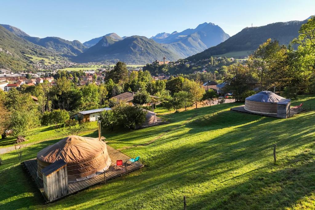 a green field with two yaks and mountains in the background at Yourtes Olachat proche Annecy in Faverges