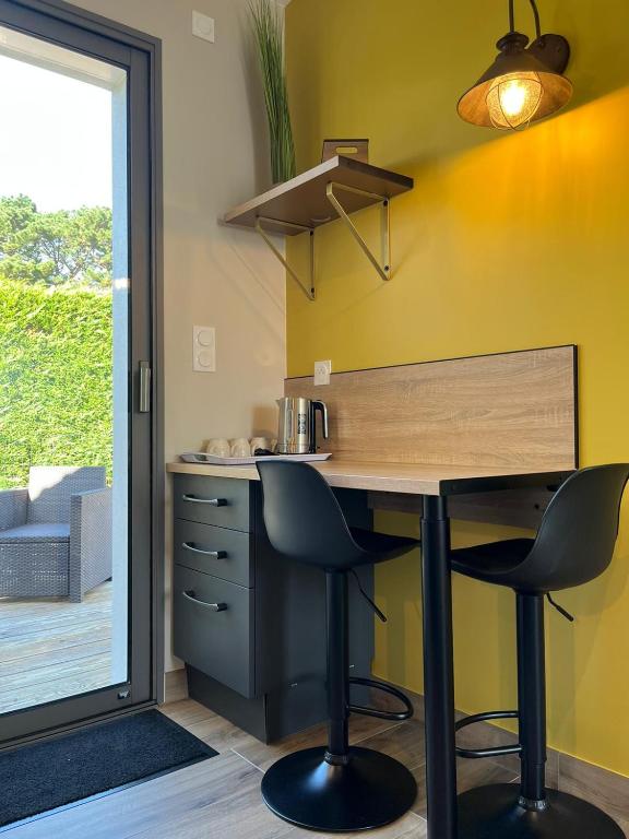 une cuisine avec un bureau avec deux chaises et une fenêtre dans l'établissement Sun Oasis Le Cocon, à Bretignolles-sur-Mer