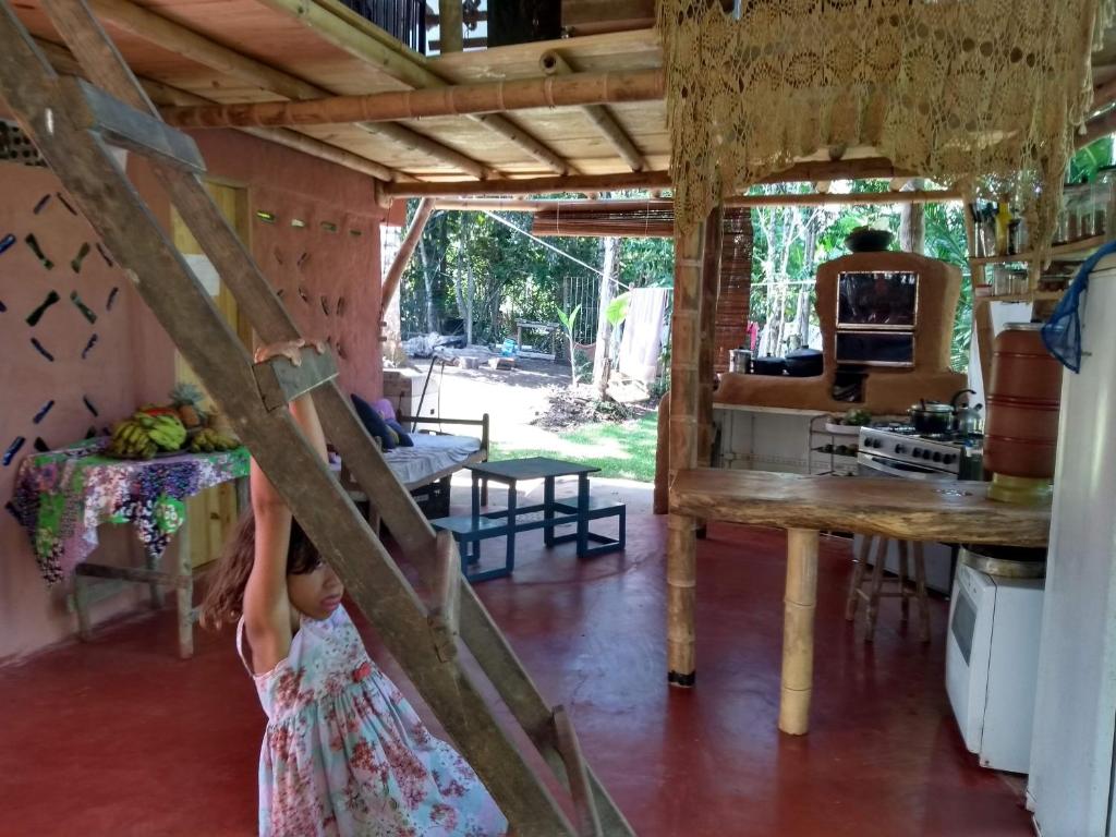 Ein kleines Mädchen steht hinter einer Tür in einem Raum in der Unterkunft Casa de bambu e garrafas no litoral de Serra Grande in Uruçuca