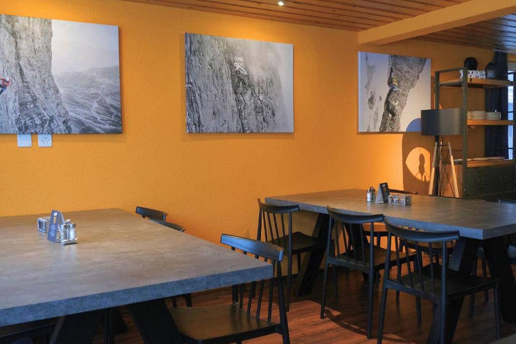 two tables and chairs in a restaurant with orange walls at Eiger Lodge Easy in Grindelwald