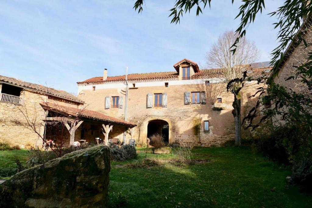 - un grand bâtiment en pierre avec une cour devant dans l'établissement La Contie, bol d'air et de nature, à Najac