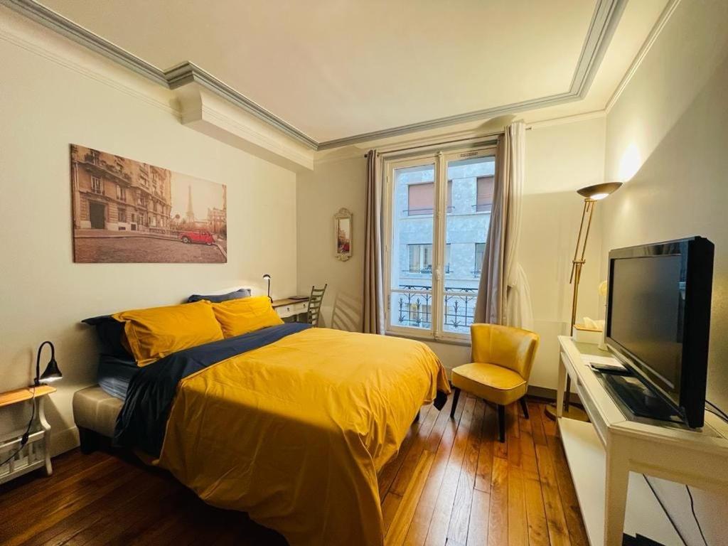- une chambre avec un lit jaune et une télévision dans l'établissement Appartement Tour Eiffel - Invalides, à Paris