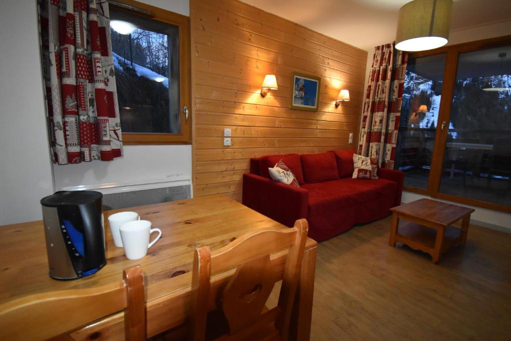 un salon avec une table et un canapé rouge dans l'établissement VAUJANYLOCATIONS - Crystal407, à Vaujany