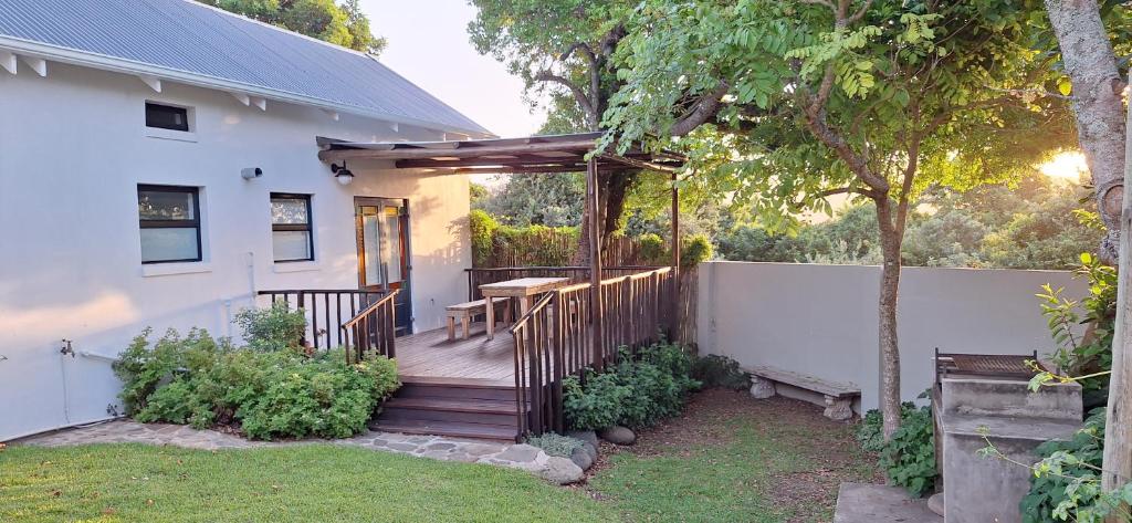 eine Holzterrasse mit Tisch und Zaun in der Unterkunft Wild Plum Cottage in Kei-mouth Village