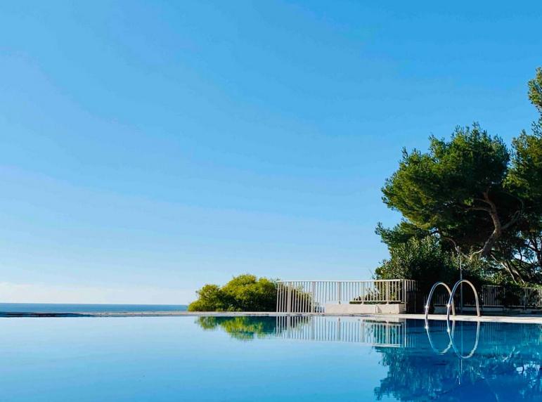 un grand bassin d'eau avec une clôture et des arbres dans l'établissement Résidence Athéna Port, à Bandol