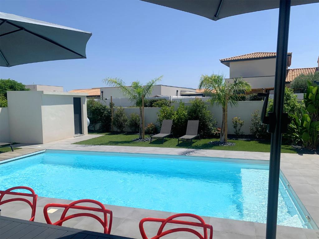 une piscine avec des chaises et un parasol dans l'établissement Villa Plein Sud, à Villeneuve-de-la-Raho