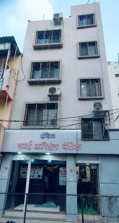 a tall white building with a sign in front of it at Arihant palace in Shirdi