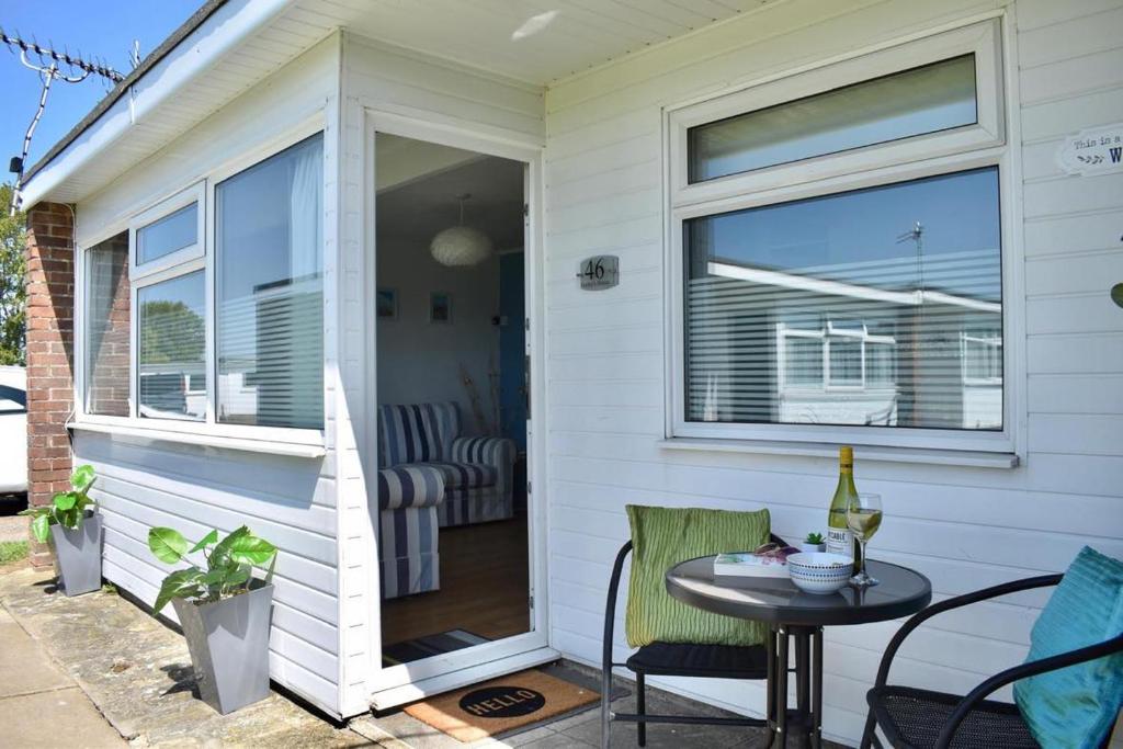 a patio with a table and chairs and a window at 46 Hectors, Sunbeach, Scratby - Two bed chalet, sleeps 4, pet friendly, free Wi-Fi, free entry to onsite clubhouse and bed linen and towels included in Great Yarmouth