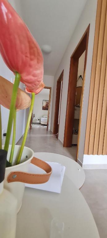 a pink flower in a white vase on a table at A JÓIA de Itapoá a Passos da Praia in Itapoa