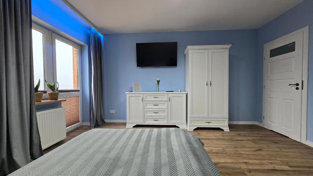 een blauwe kamer met een witte kast en een televisie bij Woodland - Apartments & SPA Łagów in Łagów