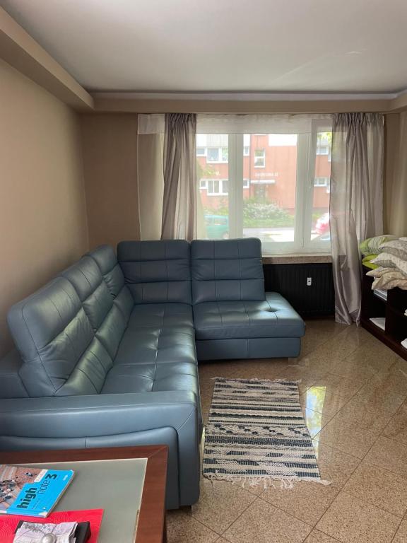 a blue couch in a living room with a window at Apartament Kołobrzeg in Kołobrzeg