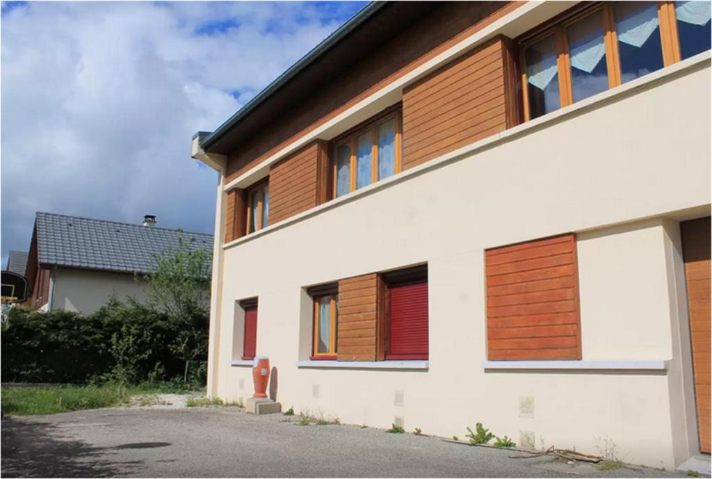 - un bâtiment blanc avec des portes et des fenêtres en bois dans l'établissement T3 Villard de Lans, à Villard-de-Lans