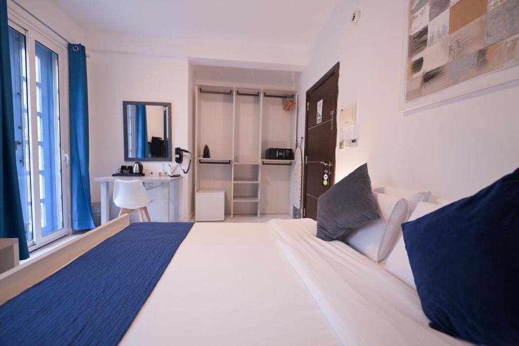 a bedroom with a large white bed with blue pillows at The Exiles Hotel in Sliema