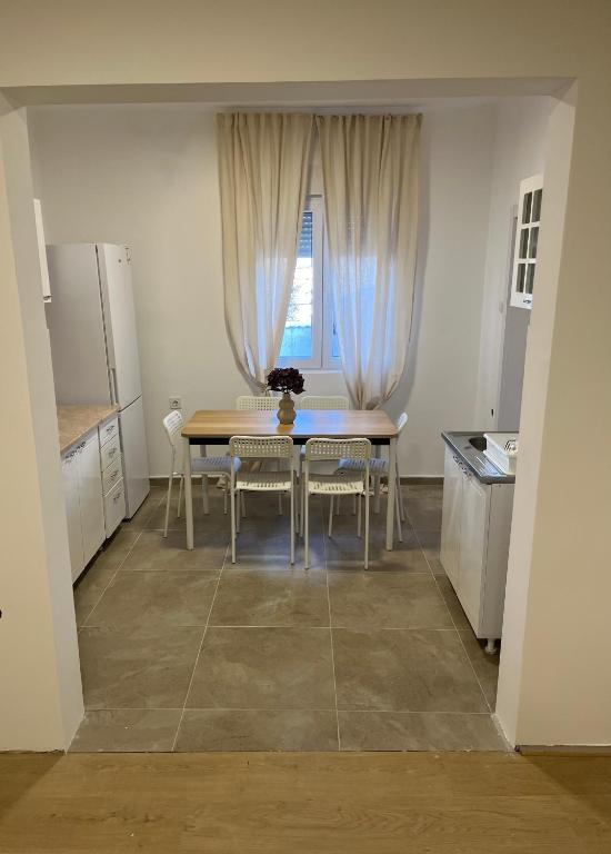 Una cocina con mesa y sillas y una ventana. en Trosobni apartman, en Belgrado
