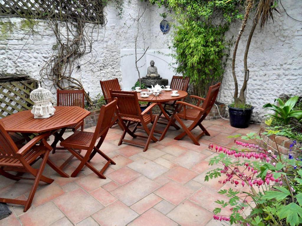 un patio avec une table, des chaises et une fontaine dans l'établissement Clifton Cottage - by Brighton Holiday Lets, à Brighton et Hove