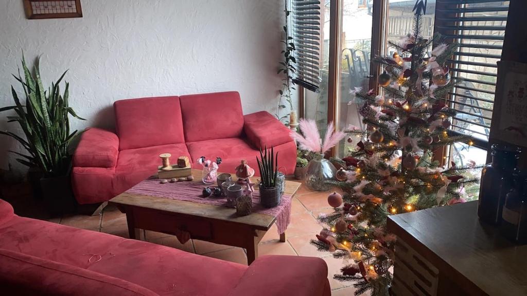 - un salon avec un canapé rouge et un arbre de Noël dans l'établissement La maison aux quatres lavandes, à Neuve-Église