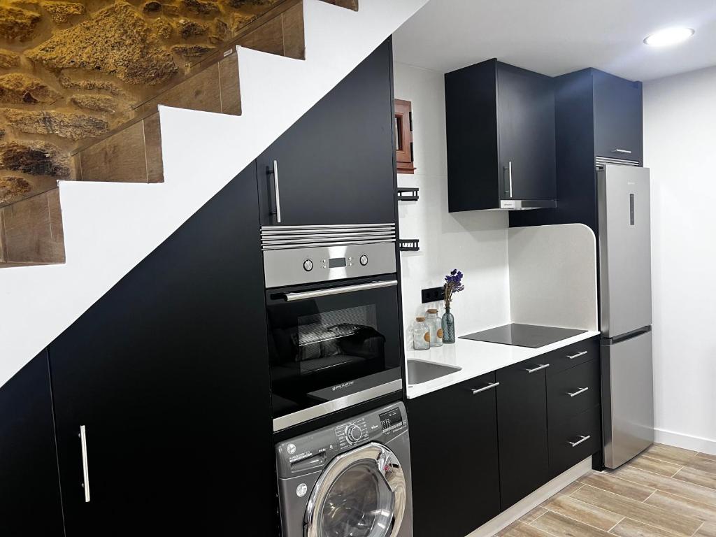 a kitchen with black cabinets and a washer and dryer at Casa Cuchariños Louro in Louro