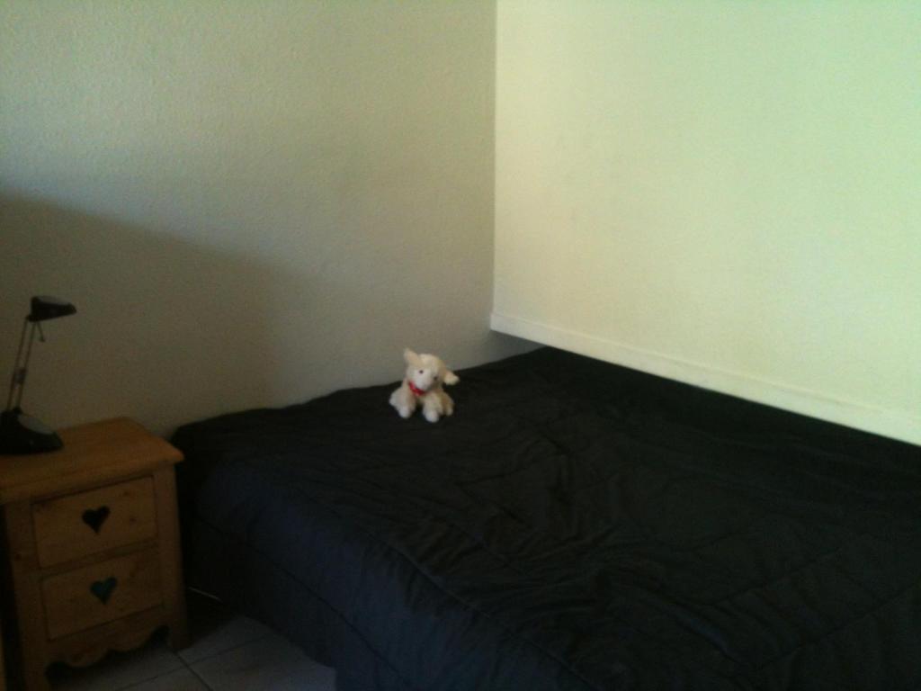 un ours en peluche assis sur un lit dans l'établissement Pied de Piste, Ski Briançon !, à Briançon