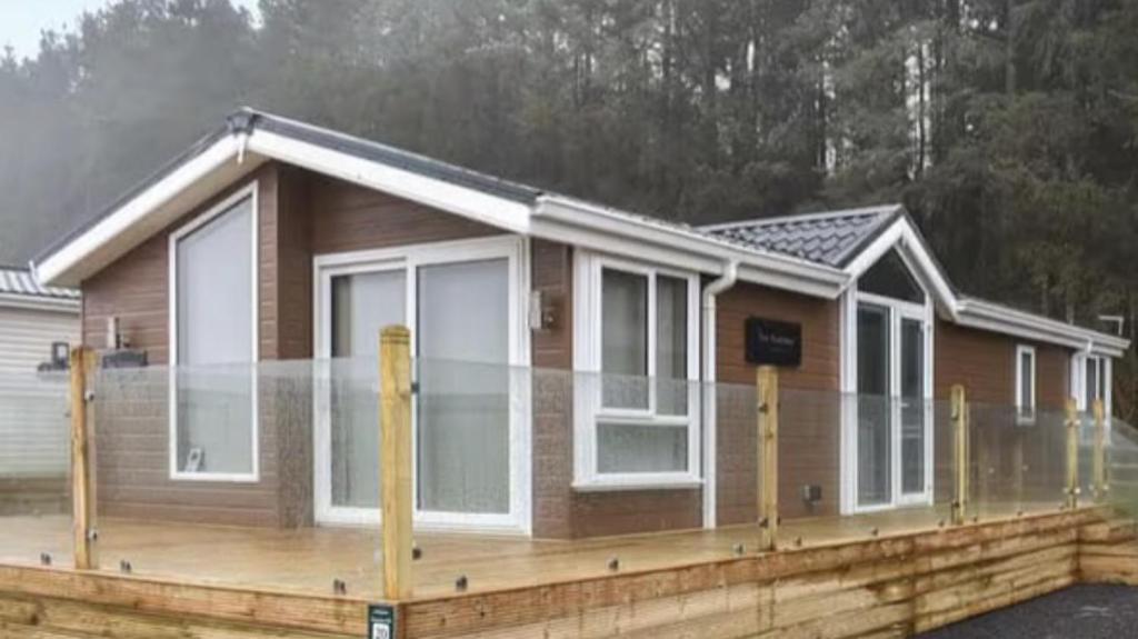 a house with white windows on a wooden deck at Woodland Lodge in Plumbland