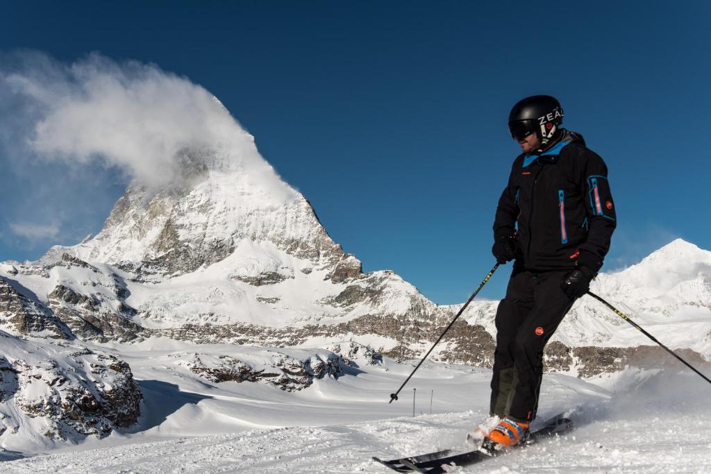 a man on skis standing on a snowy mountain at Le Petit CHARME-INN in Zermatt